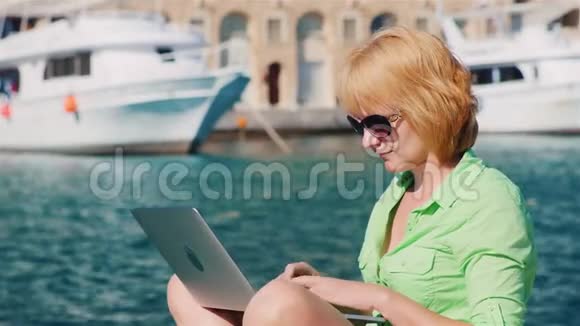 女游客使用笔记本电脑背景的城市景观与游艇视频的预览图