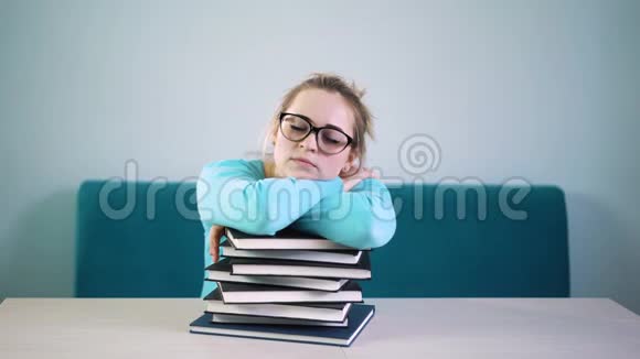一个戴着眼镜睡在图书馆书上的疲惫的学生女孩视频的预览图