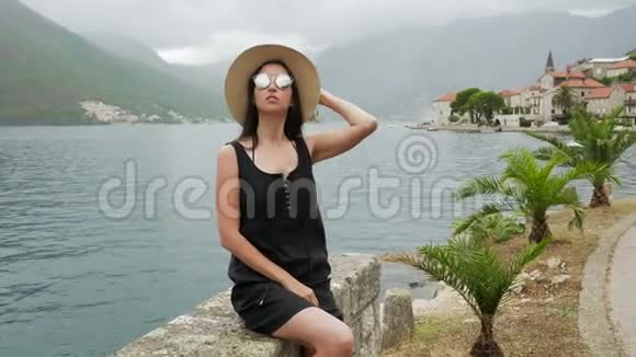女孩坐在水边戴着草帽穿着黑色连衣裙视频的预览图