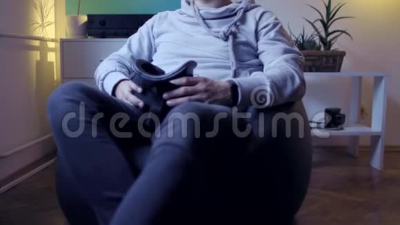 穿着懒包的男人在家里玩虚拟现实游戏视频的预览图