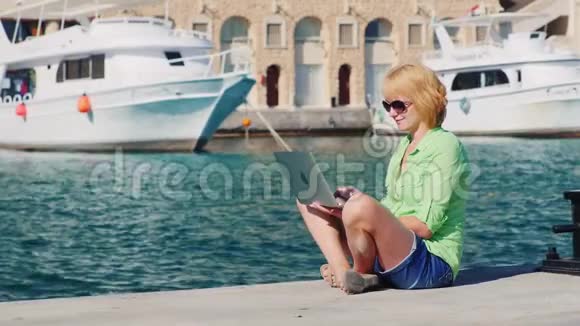 女游客使用笔记本电脑背景的城市景观与游艇视频的预览图