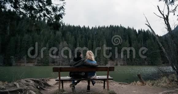 年轻夫妇坐在木凳上看着湖边彼此相爱视频的预览图
