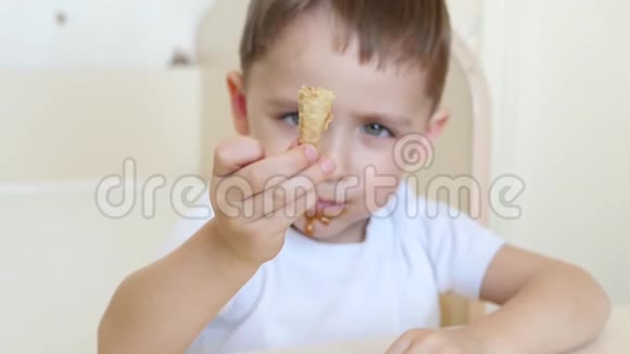 孩子坐在一张桌子旁在华夫饼锥里愉快地吃着巧克力冰淇淋这孩子很快乐这就是视频的预览图