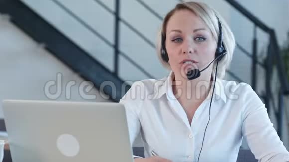 美丽的商务客服女士微笑着与呼叫中心的摄像机交谈视频的预览图