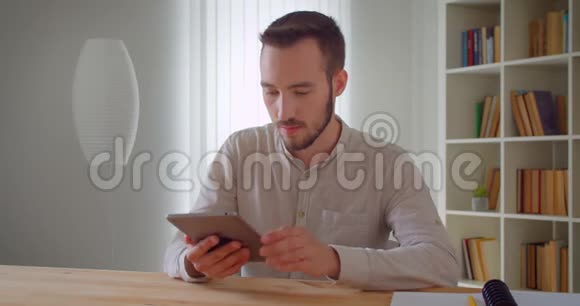 用平板电脑拍摄年轻英俊的高加索商人的特写肖像并在室内拍摄绿色屏幕视频的预览图