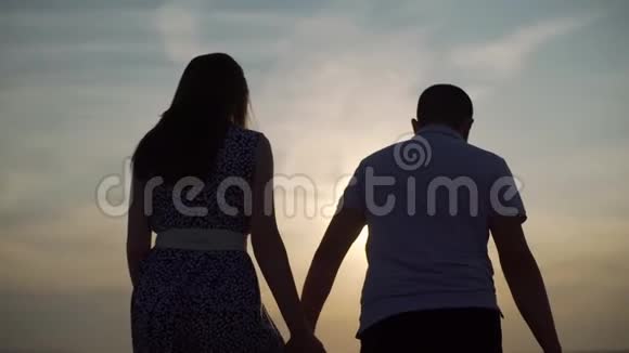 日落时分一对夫妇沿着沙滩散步视频的预览图