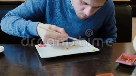 年轻的黑发男人吃盘子里的碎屑用舌头舔盘子视频的预览图