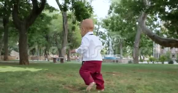 第一步好奇的小男孩赤脚走在草地上视频的预览图