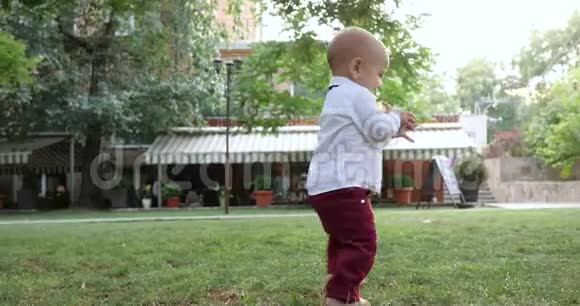 慢动作的视频片段孩子的第一步迷人的孩子独自赤脚在绿草上行走视频的预览图