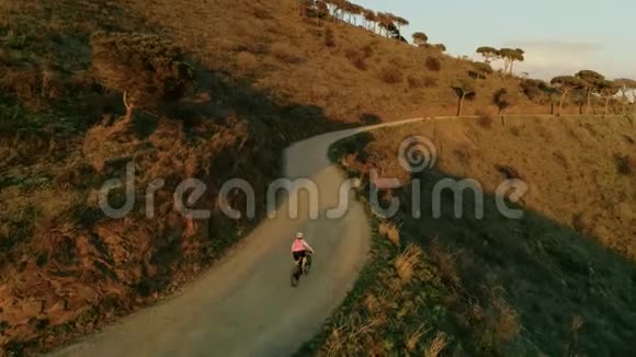 日落时分骑自行车的女子无人机镜头视频的预览图