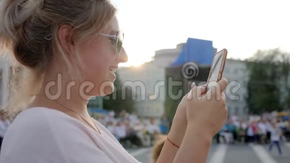 戴太阳镜的微笑女性在站在市中心的手机上留言视频的预览图