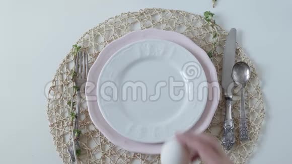 桌子设置白色背景上的白色菜肴早餐煮鸡蛋雌性的手在盘子里产卵视频的预览图