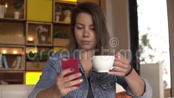 年轻女子坐着智能手机喝咖啡视频的预览图