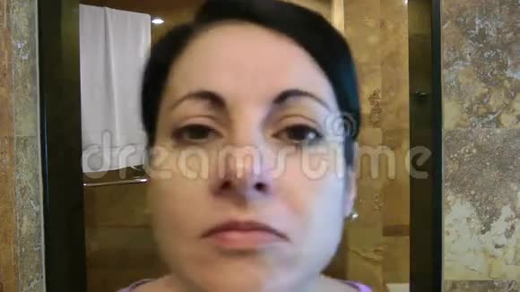 女人在浴室里看着她的脸视频的预览图