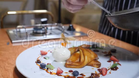 最后的触摸概念厨师把焦糖酱倒入带有甜点的盘子里冰淇淋煎饼和浆果视频的预览图