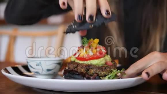 年轻的高加索女人在餐厅吃健康美味的素食黑汉堡4K视频的预览图