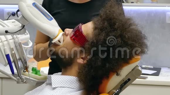 一个年轻人在牙医面前擦牙的侧面镜头视频的预览图
