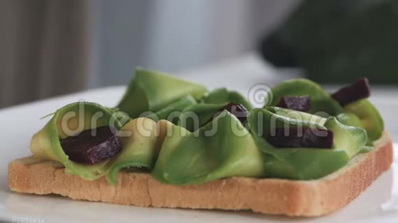 一位妇女正在准备早餐用鳄梨和甜菜根做三明治的手的特写镜头视频的预览图