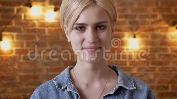 年轻漂亮的短发时髦女孩在镜头前看着微笑着砖背景视频的预览图