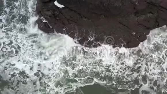 海浪在黑色的岩石上奔跑破碎成飞溅视频的预览图