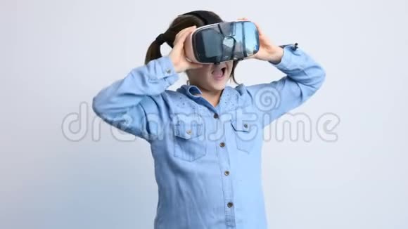 灰色背景下戴虚拟现实耳机的可爱小女孩视频的预览图