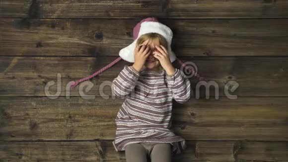 头顶上幸福微笑的女孩子戴着帽子玩着老式木制背景上的装饰品文字或徽标复制空间视频的预览图