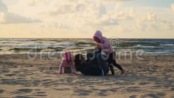 日落时分妈妈和两个女儿在沙滩上玩耍视频的预览图