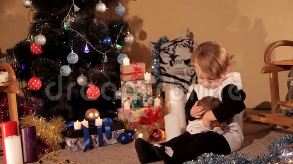小女孩带着新年礼物在圣诞树旁玩耍视频的预览图