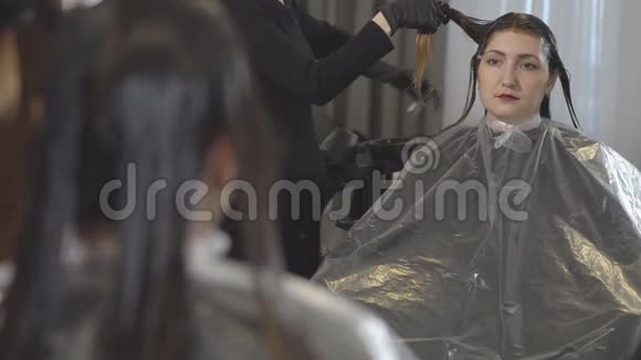 美容院的年轻女子头发护理镜子里的倒影视频的预览图