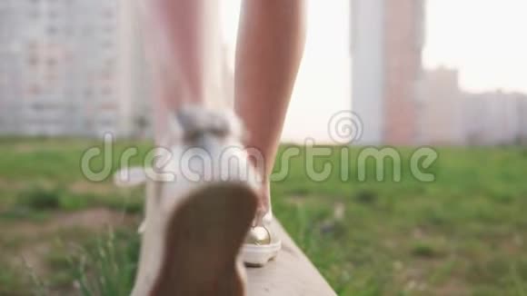 小女孩在城市荒地上的水泥原木上行走的特写腿视频的预览图
