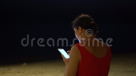 傍晚海滩上的那个女人越南海滩那个女人晚上手里拿着智能手机那个女人视频的预览图
