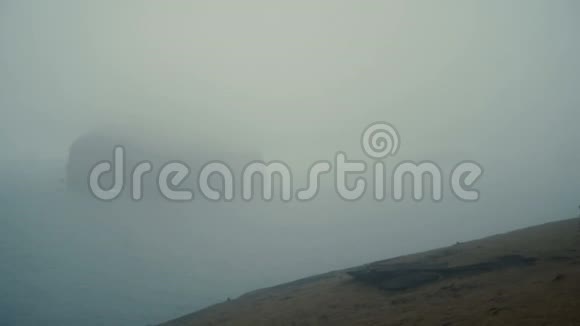 在雾蒙蒙的白天年轻的女人站在海边欣赏冰岛的风景想着什么视频的预览图
