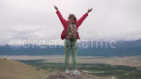 带背包的旅游女孩站在悬崖边欣赏山谷的开阔景色a视频的预览图