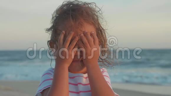 快乐的小女孩看着镜头在沙滩上笑的肖像视频的预览图