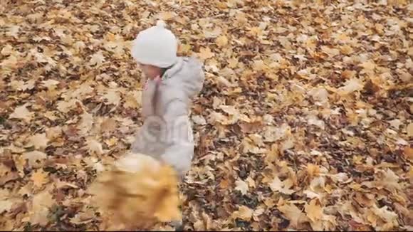 快乐的小女孩在公园里和秋天的叶子一起旋转视频的预览图