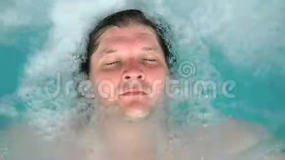 这个人躺在按摩浴缸里放松闭上眼睛白种人躺在游泳池里躺在水里从这里看视频的预览图