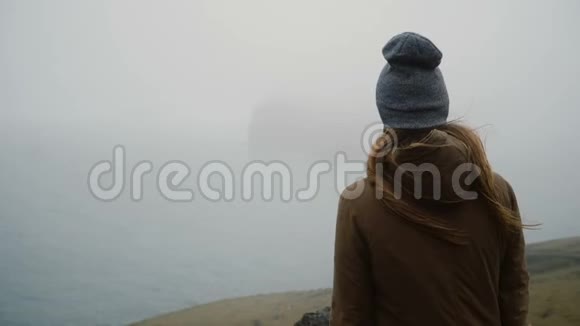 后景年轻女子戴着帽子站在海边想着什么探索冰岛视频的预览图
