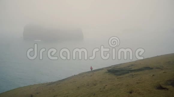 年轻的旅行者在雾中漫步在海边在阴天的冰岛靠近维斯特曼那耶尔探索海滩视频的预览图