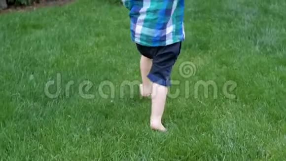 赤脚2岁男孩在公园草地上奔跑的慢动作视频视频的预览图