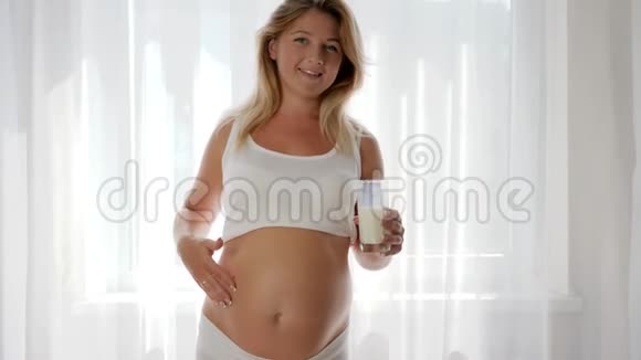 未来的母亲在镜头前微笑着喝着奶制品孕妇拿着杯子视频的预览图