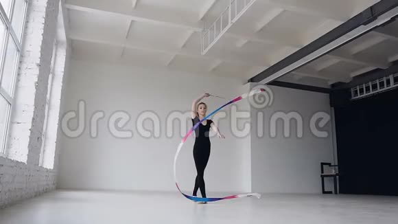 黑色身体的可爱体操在白色工作室里用彩色丝带进行体操运动可爱的女孩视频的预览图
