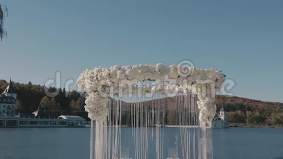 结婚祭坛水晶链挂在婚礼祭坛上上面挂着白玫瑰而它站在外面的湖岸上视频的预览图