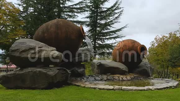 创意陶罐喷泉周围有巨大的石头位于绿色公园艺术视频的预览图