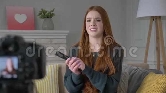 年轻的红发女孩博客作者微笑着对着镜头说话展示了一种新的购买化妆品基础遮瑕剂视频的预览图