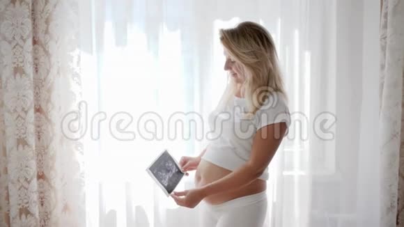 孕妇孕妇在腹部附近的摄像头上显示婴儿超声波扫描视频的预览图