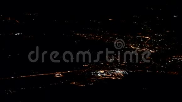 夜晚的城市灯光在飞机机翼下的黑暗中闪烁视频的预览图