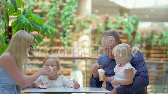小女孩在大购物中心吃冰淇淋和一个喇叭家人在商场里吃冰淇淋家庭幸福可爱视频的预览图