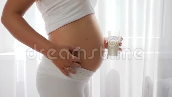 美丽的孕妇揉揉肚子喝牛奶视频的预览图