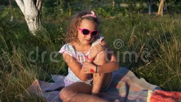 一个女学生坐在草地上晒日光浴那个女孩戴着太阳镜头上绑着绷带自然野餐视频的预览图