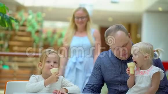 小女孩在大购物中心吃冰淇淋和一个喇叭家人在商场里吃冰淇淋家庭幸福快乐视频的预览图